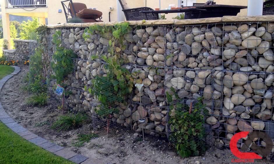 Muro feito de pedras redondas, preso com rede de arame de aço (gabião de  pedra de ferro)