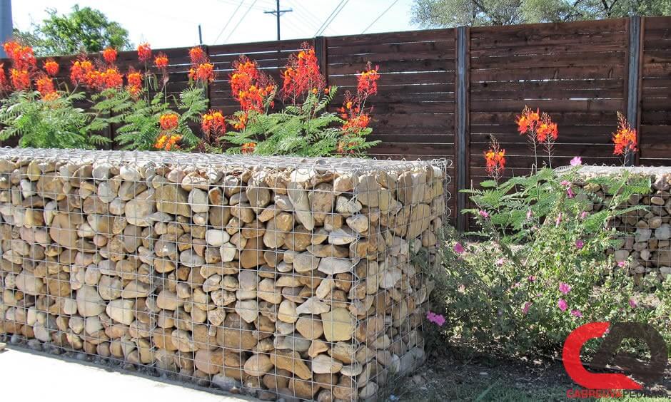 Muro feito de pedras redondas, preso com rede de arame de aço (gabião de  pedra de ferro)