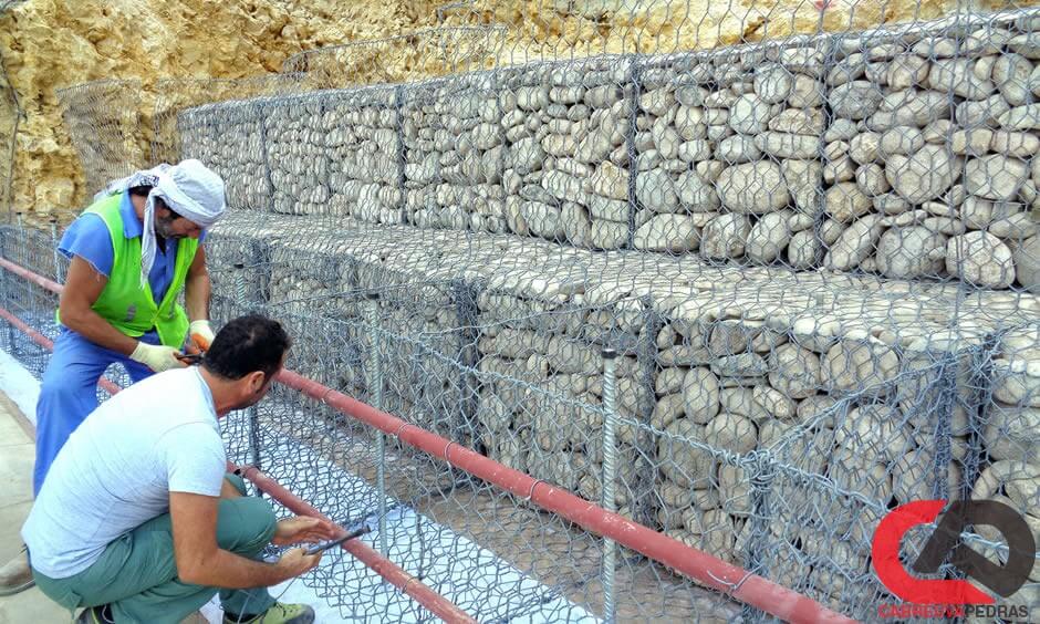 Muro feito de pedras redondas, preso com rede de arame de aço (gabião de  pedra de ferro)